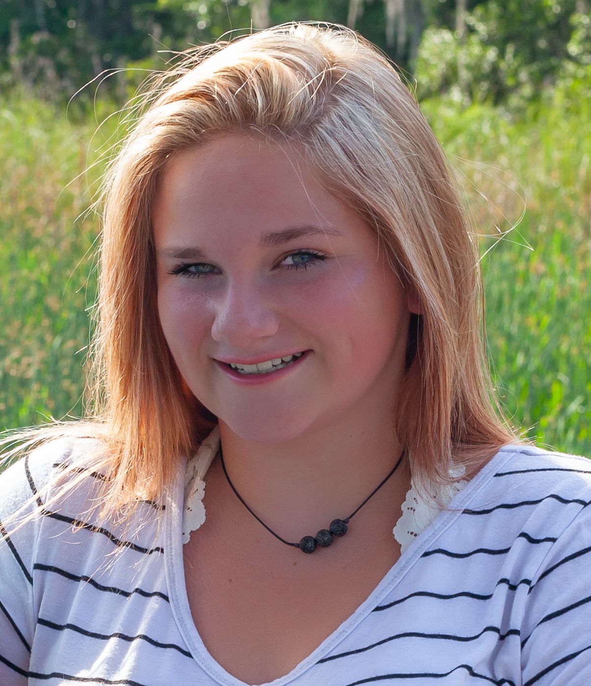 Outdoor portrait series showing warm smiles against a natural green background.