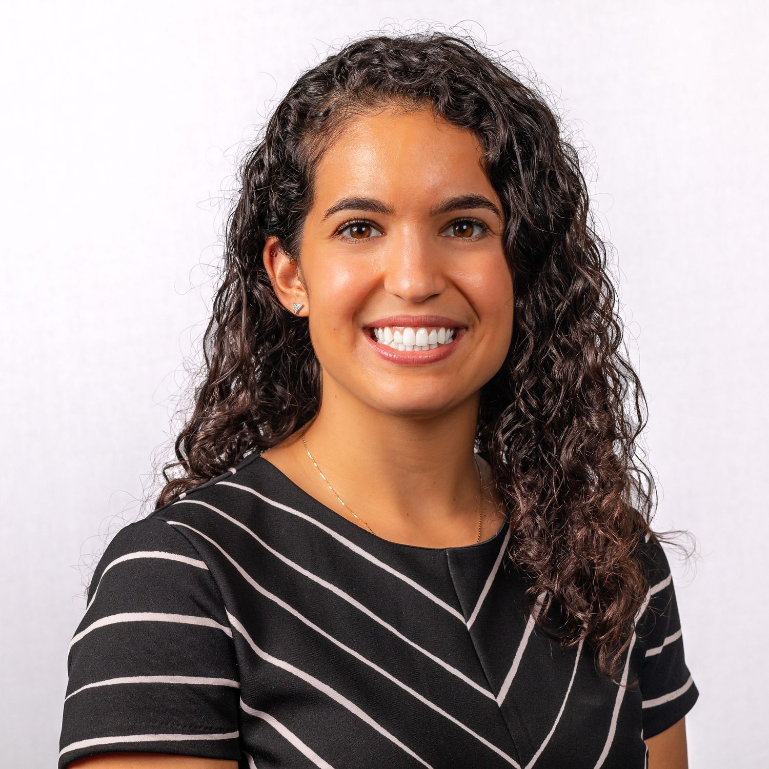 Professional portrait in black and white striped business attire against white background.