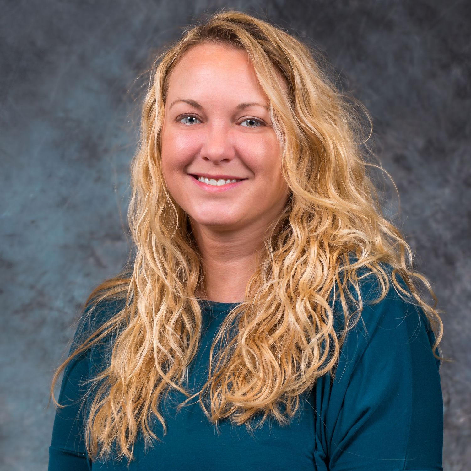 Professional portrait series showing different poses in teal top against textured blue backdrop.