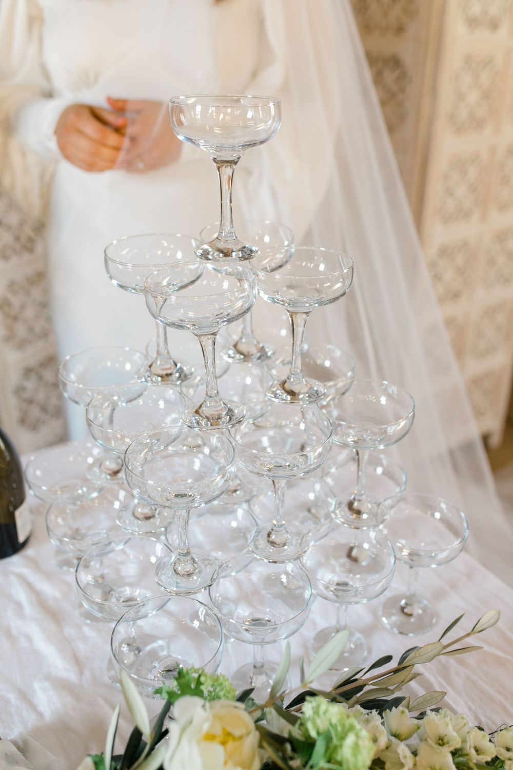 A stack of vintage champagne coupe glasses with flowers at the base.
