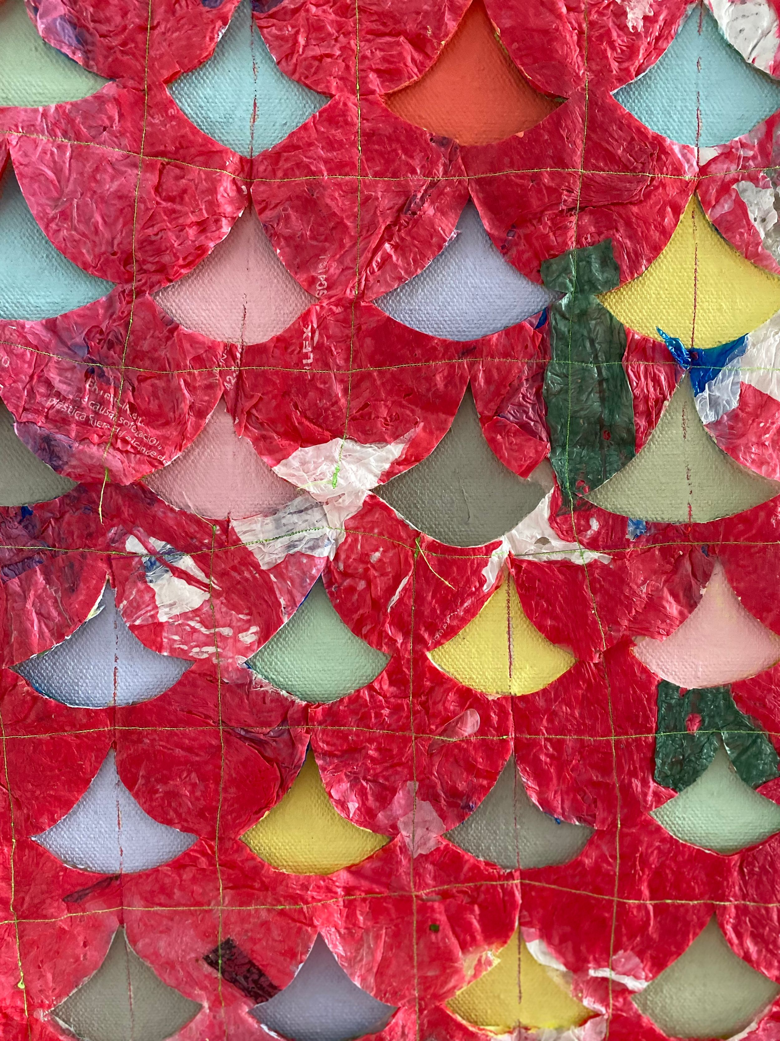 Textured red paper art installation with scalloped pattern against colorful background.