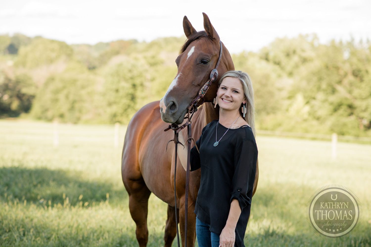 Bay horse and someone in dark sweater pose together in sunny field.