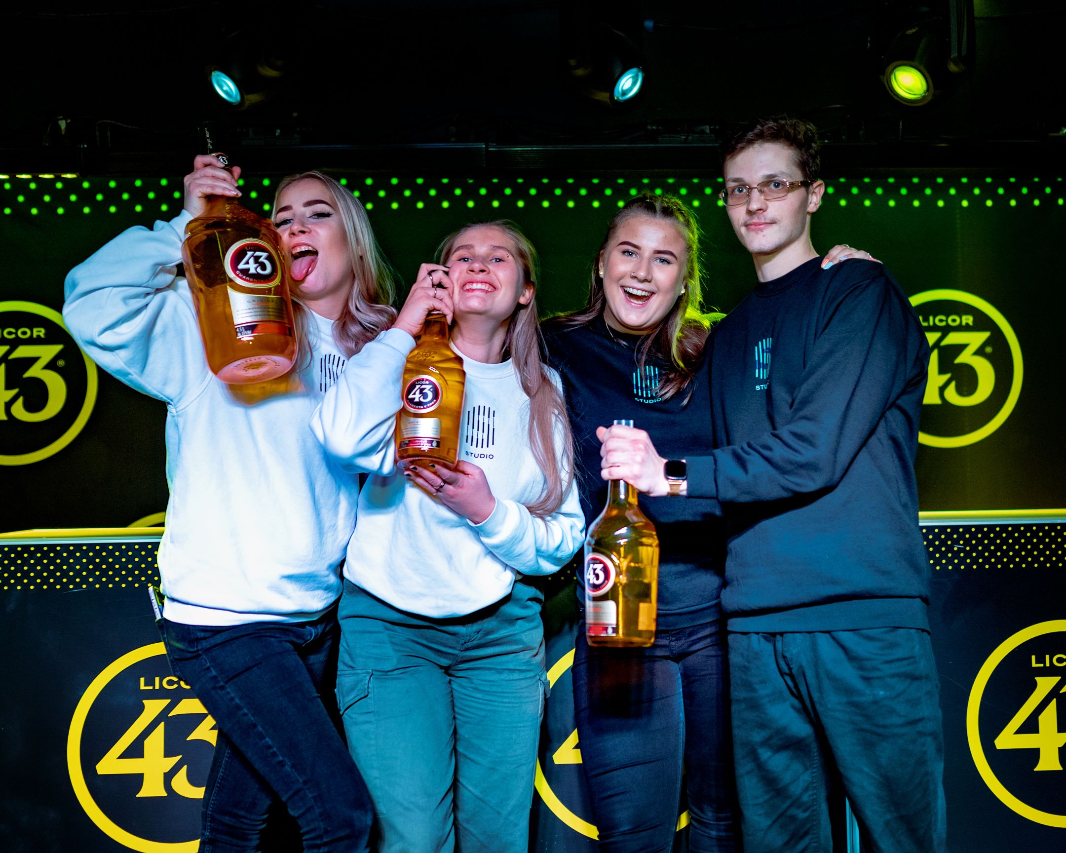 Group celebrating with Licor 43 bottles at branded nightlife event.