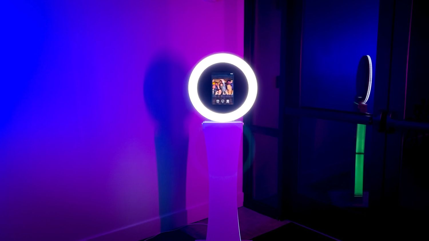 Ring light photo booth display glowing against dark background with blue and purple lighting.