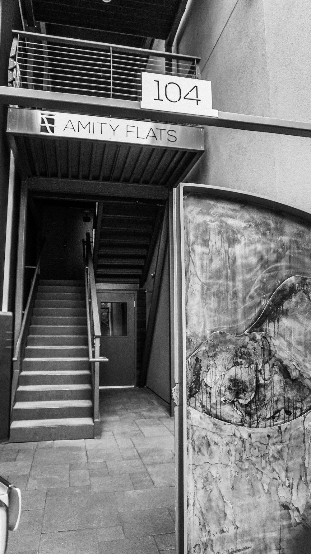 Black and white image of Amity Flats apartment building entrance with unit number 104.