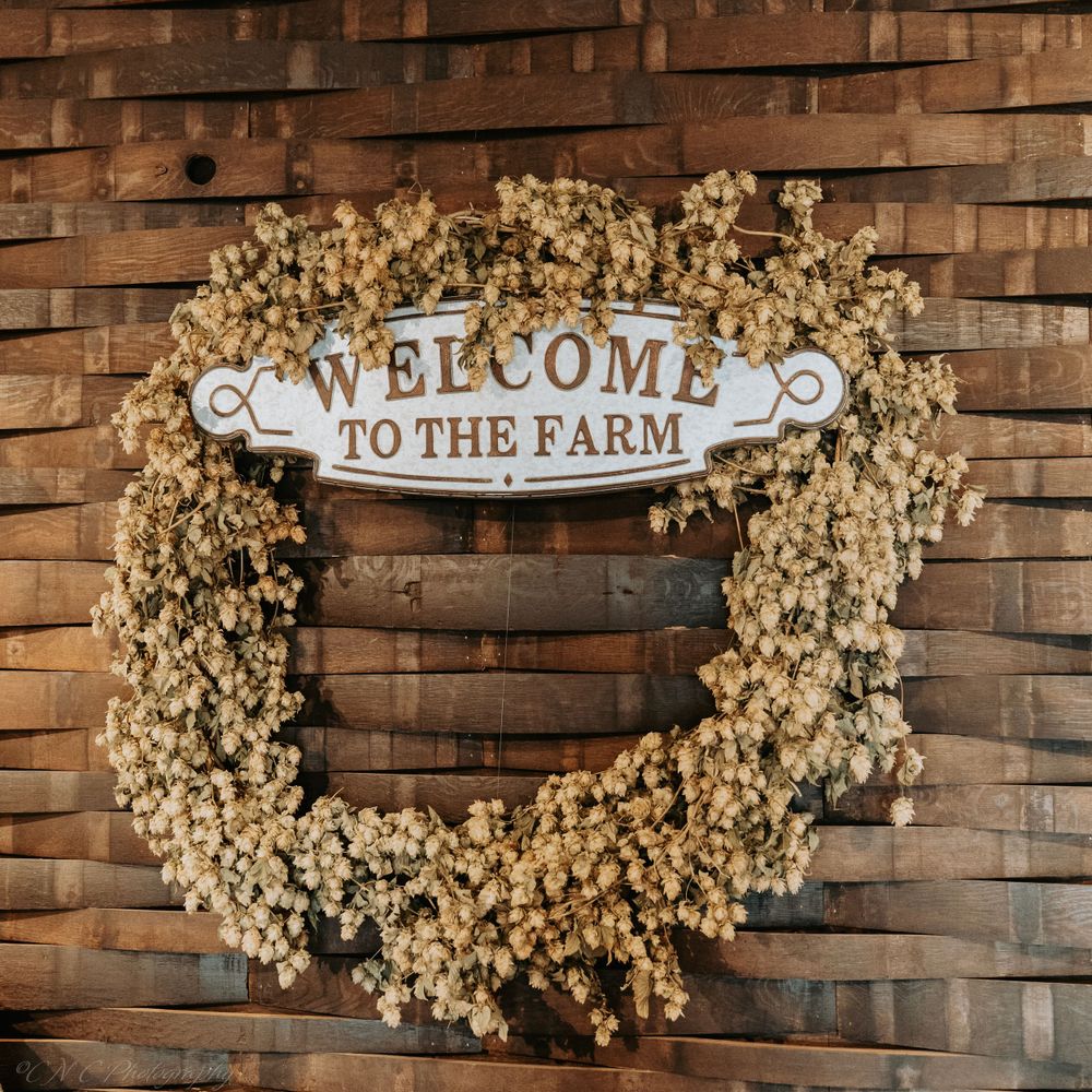 Rustic welcome sign surrounded by dried baby's breath wreath on wooden plank wall.