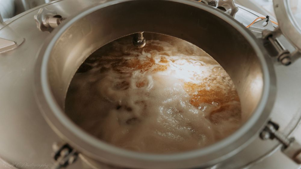 Liquid simmering in a stainless steel pressure cooker pot with steam and bubbles visible.
