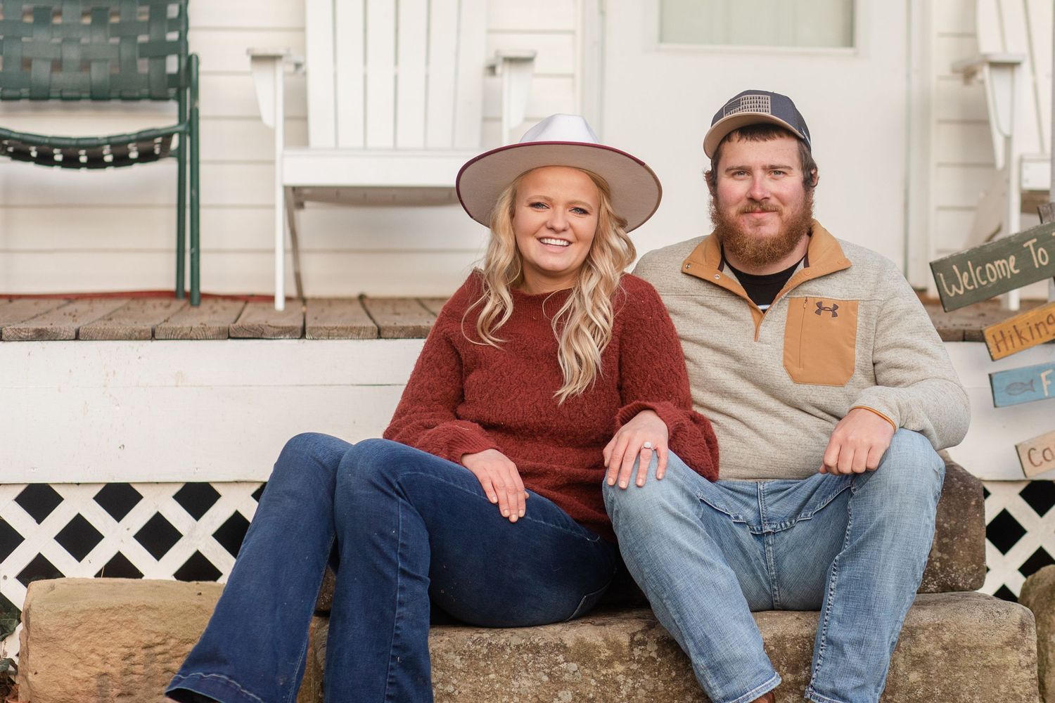 Couple sitting casually on white porch steps during an outdoor photo session.