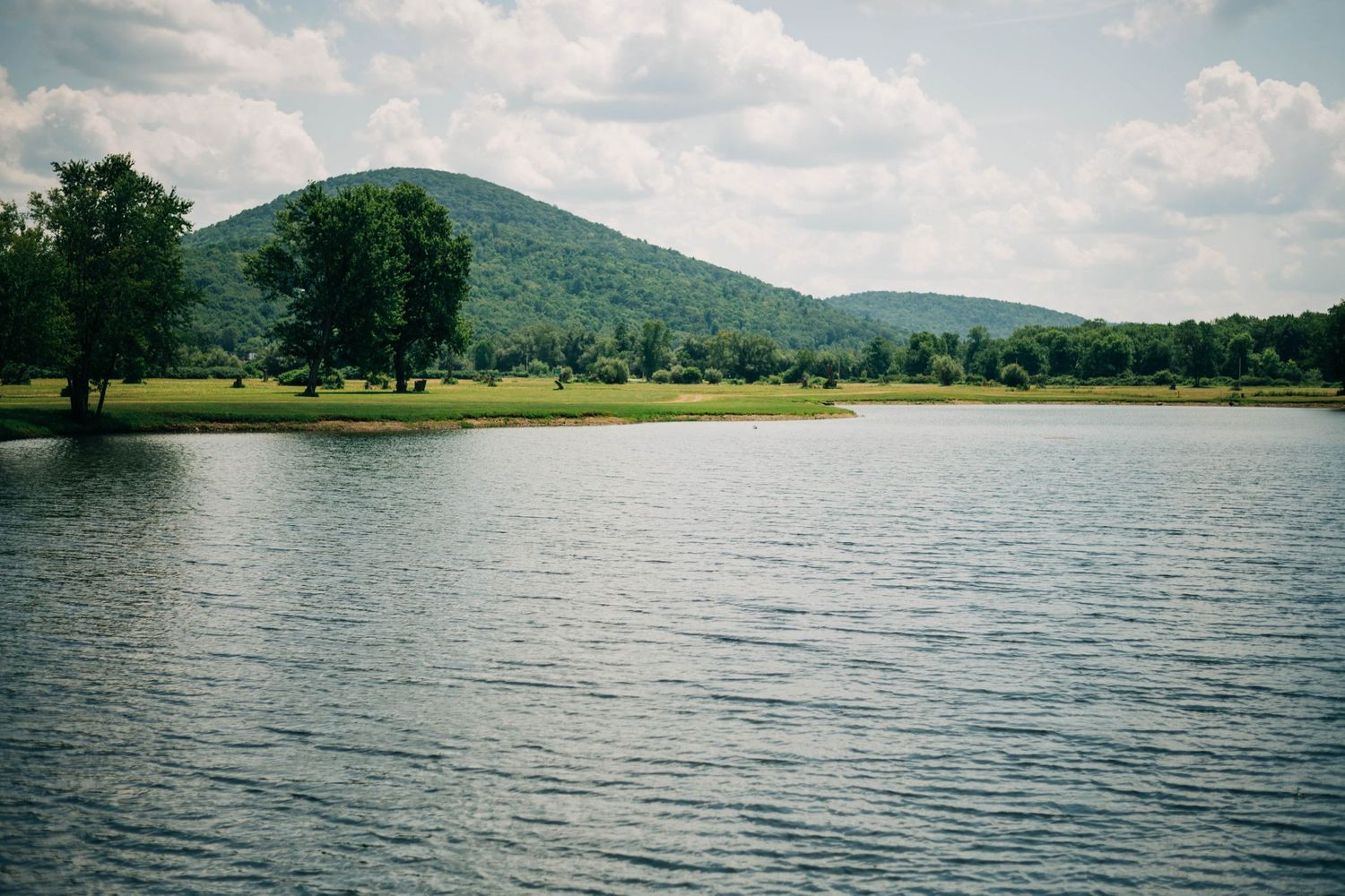 photo of lake with soft, green mountains in the background