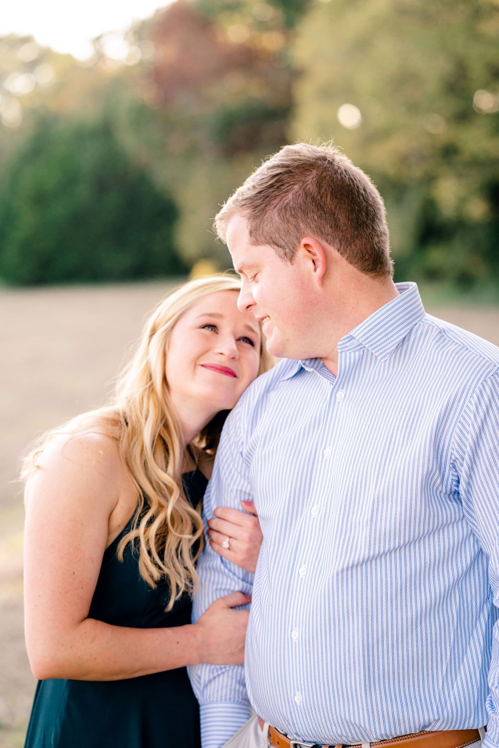 A romantic couple shares a close embrace during a sunset photoshoot outdoors.