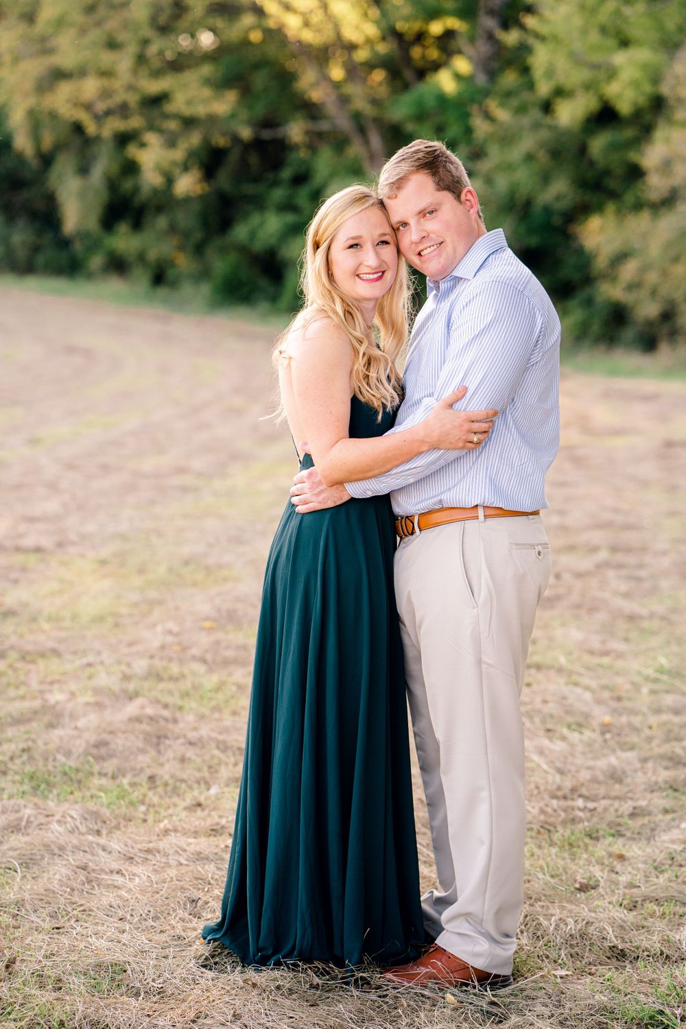 A couple poses together in formal wear during golden hour in a natural outdoor setting.
