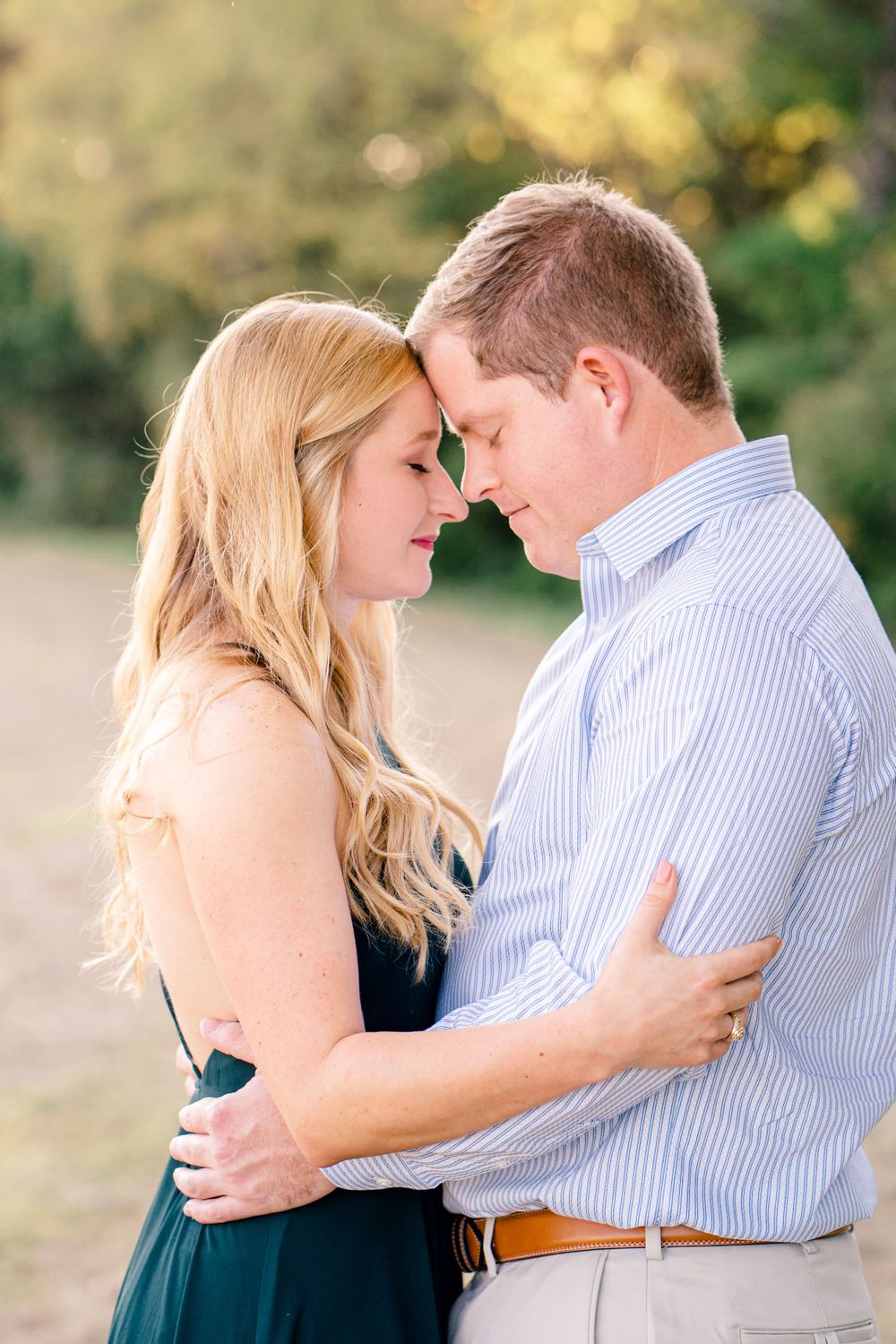 A couple shares an intimate forehead touch moment during an outdoor photoshoot.
