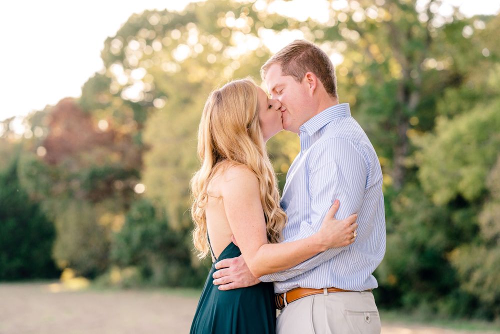 A couple in formal attire embraces during a sunset photo session outdoors.