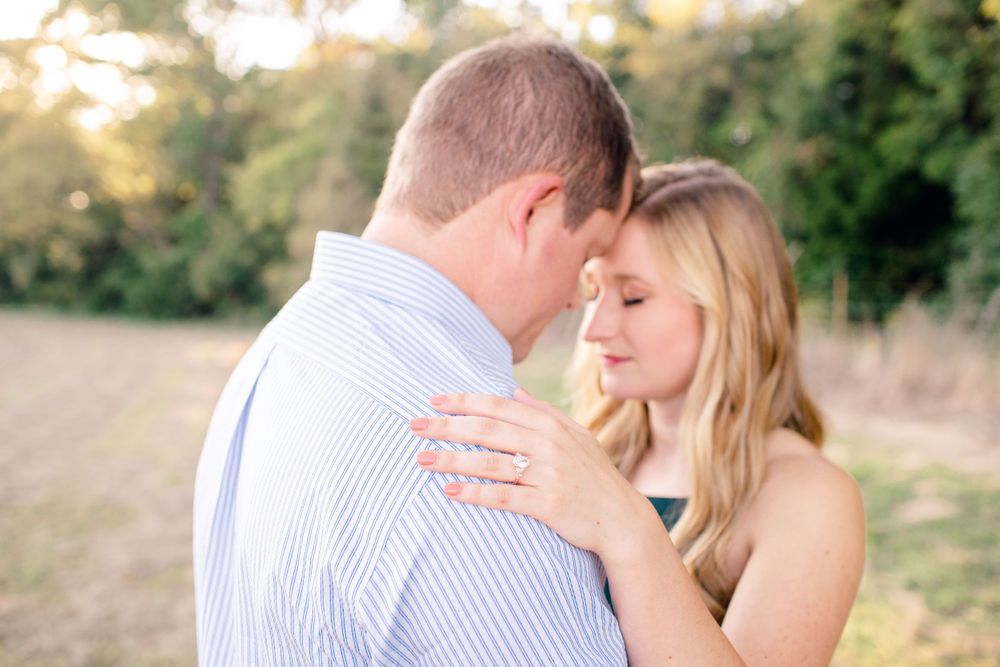 A romantic couple embraces during a golden hour photoshoot in a natural outdoor setting.