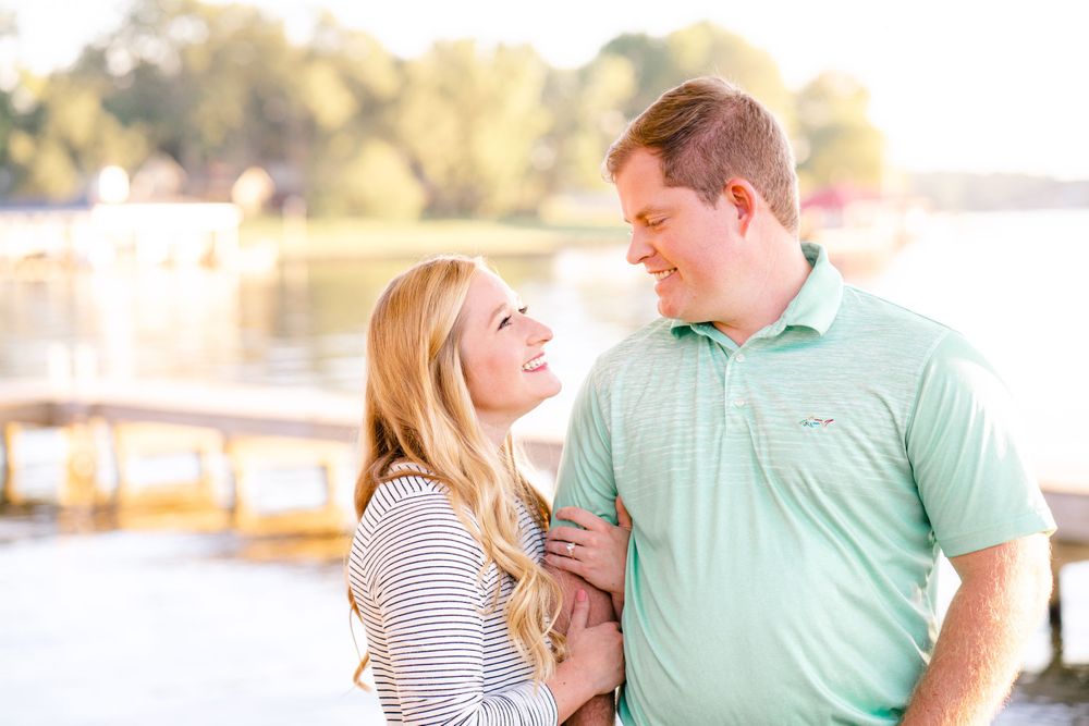 A casual couple shares a lighthearted moment by the water during sunset.