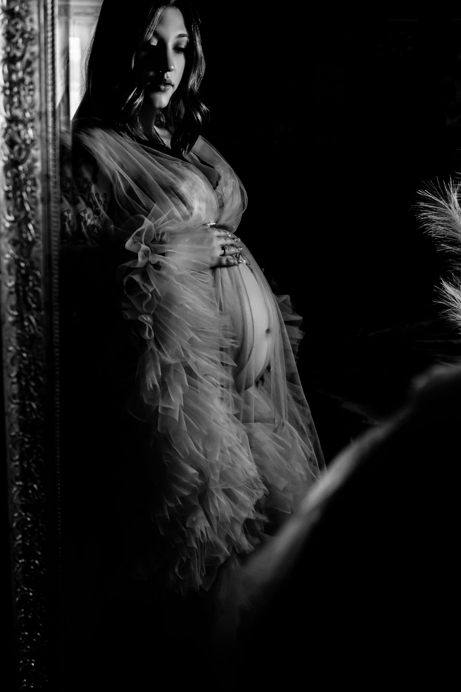 Dramatic black and white maternity portrait with flowing sheer fabric.