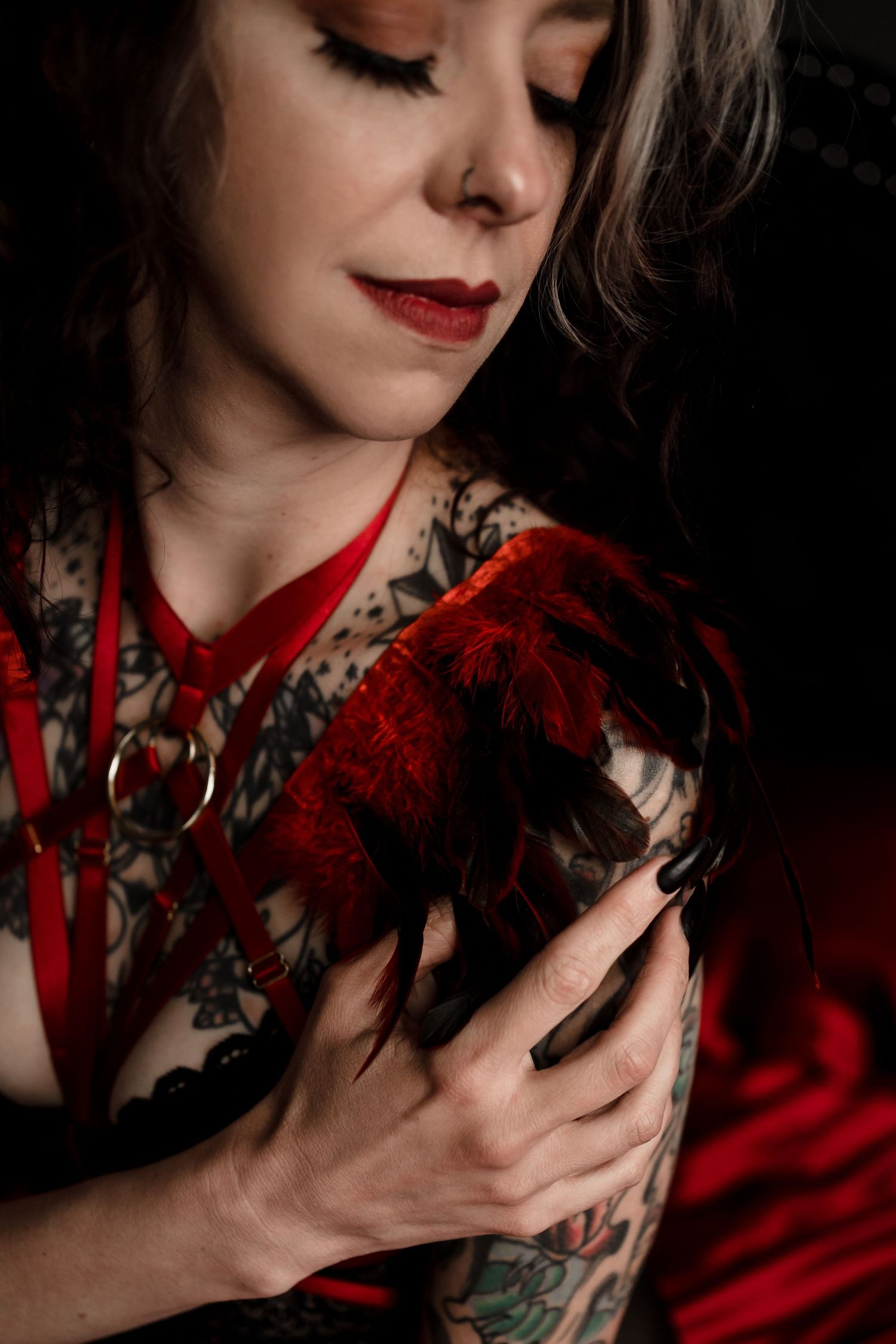 Artistic boudoir portrait featuring red fabric and floral tattoo details in moody lighting.
