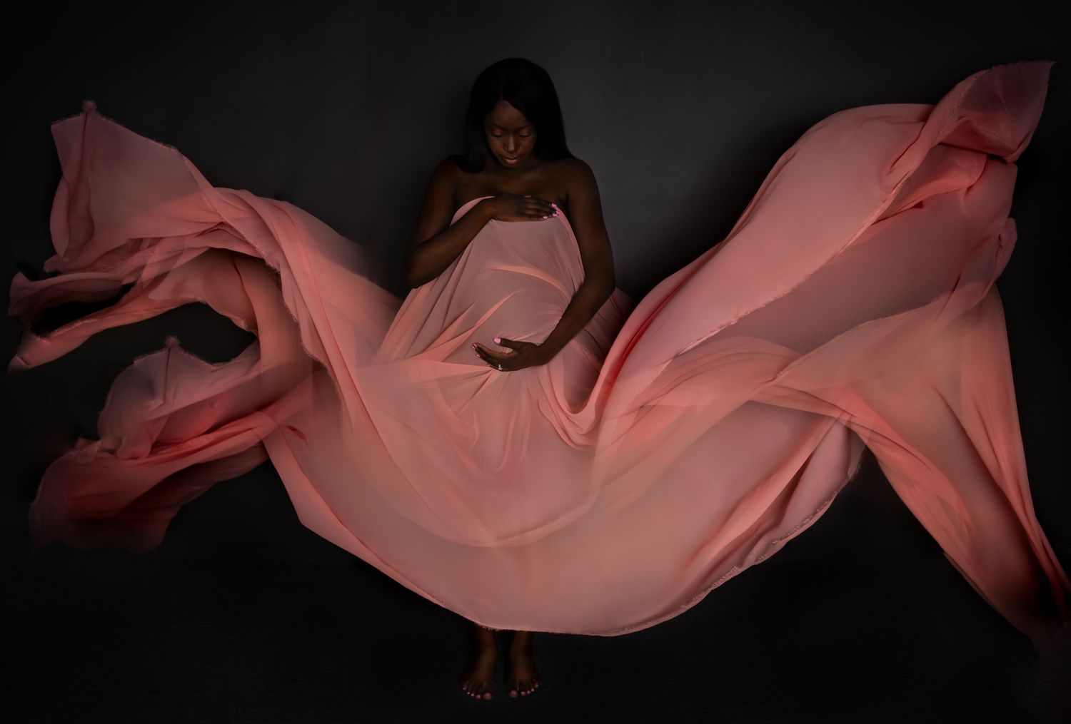 Flowing pink fabric creating elegant waves against a dark background.