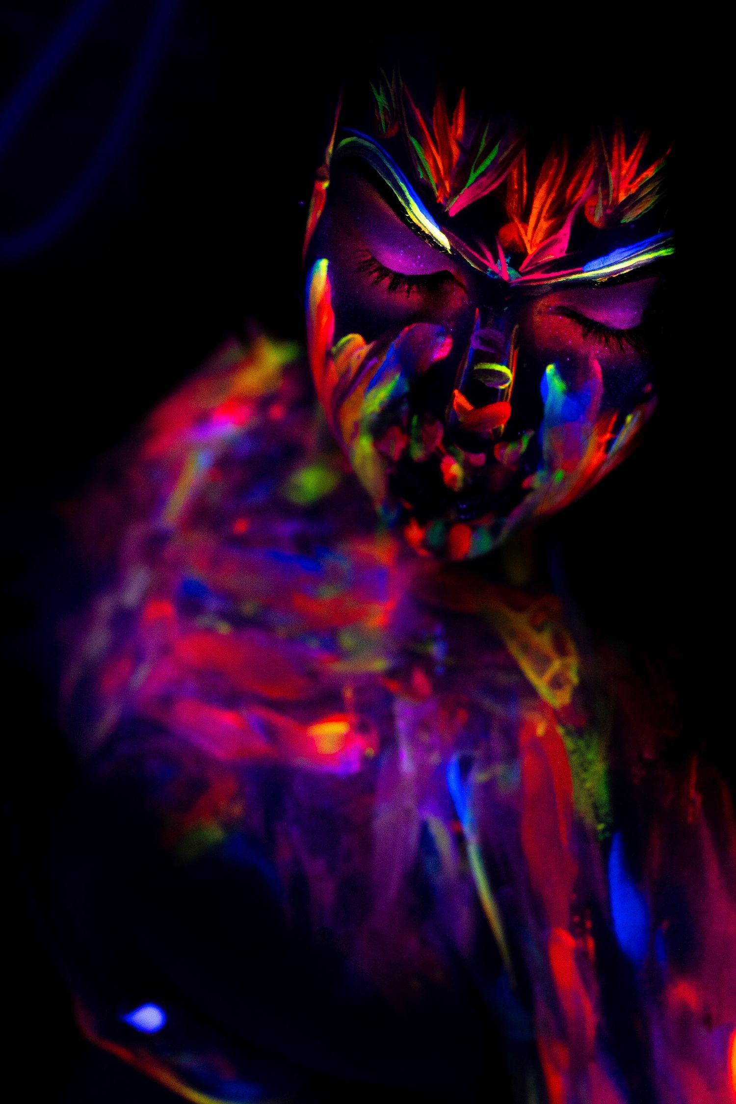 Colorful UV body paint photography with flowing rainbow patterns in darkness.