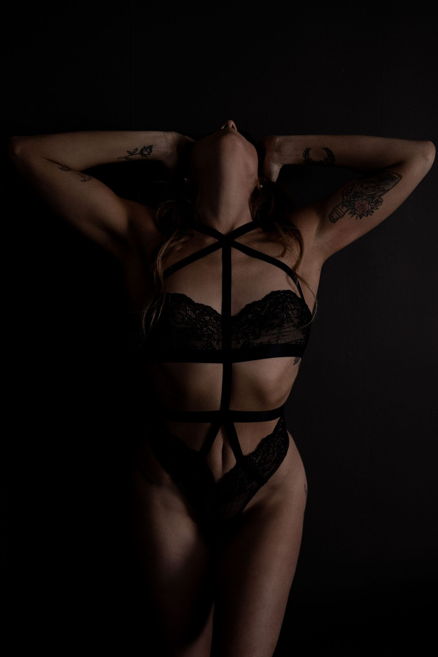 Intimate boudoir photography with dramatic shadows and black lingerie.