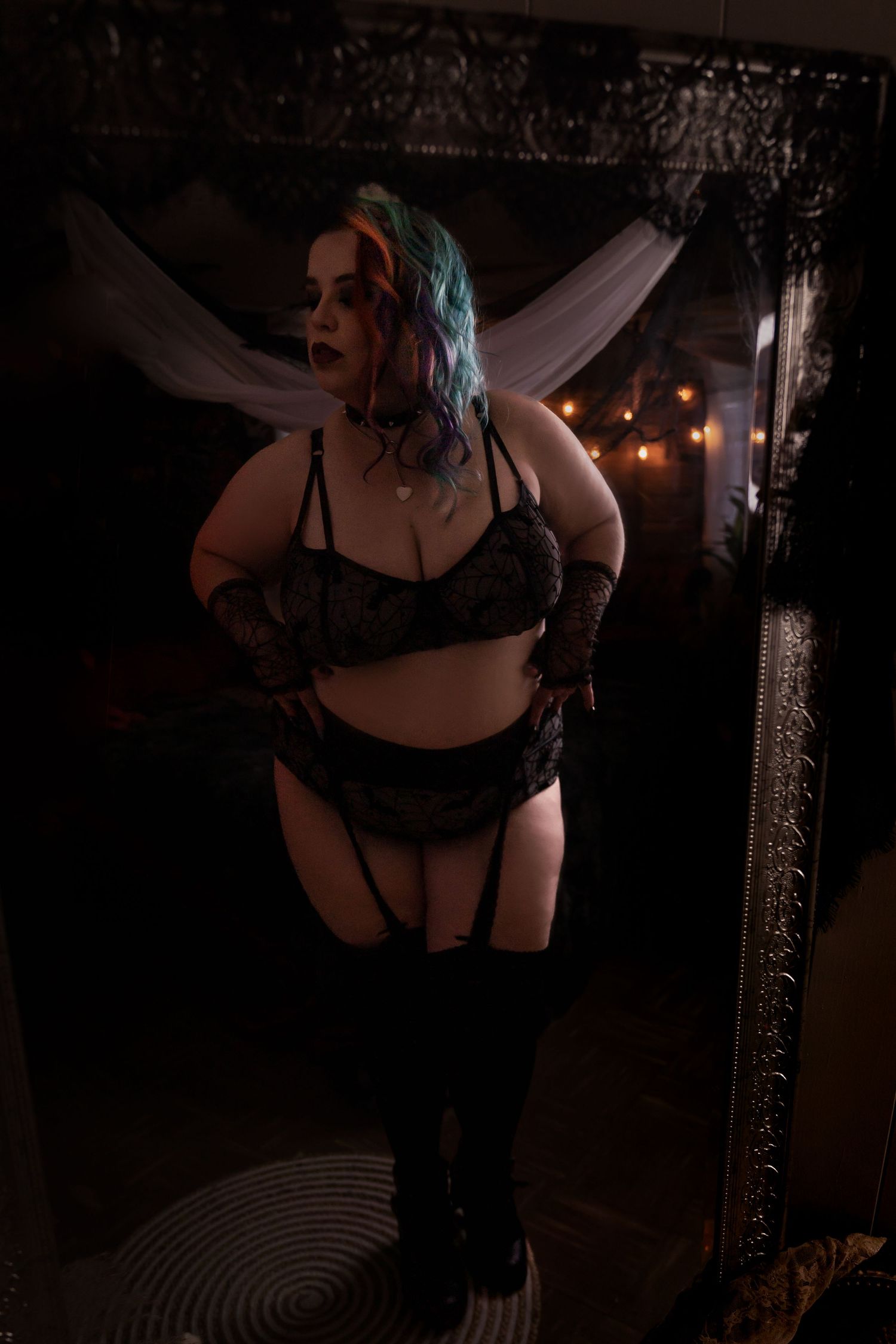 Dramatic full-length boudoir photo with black lingerie and white fabric backdrop.