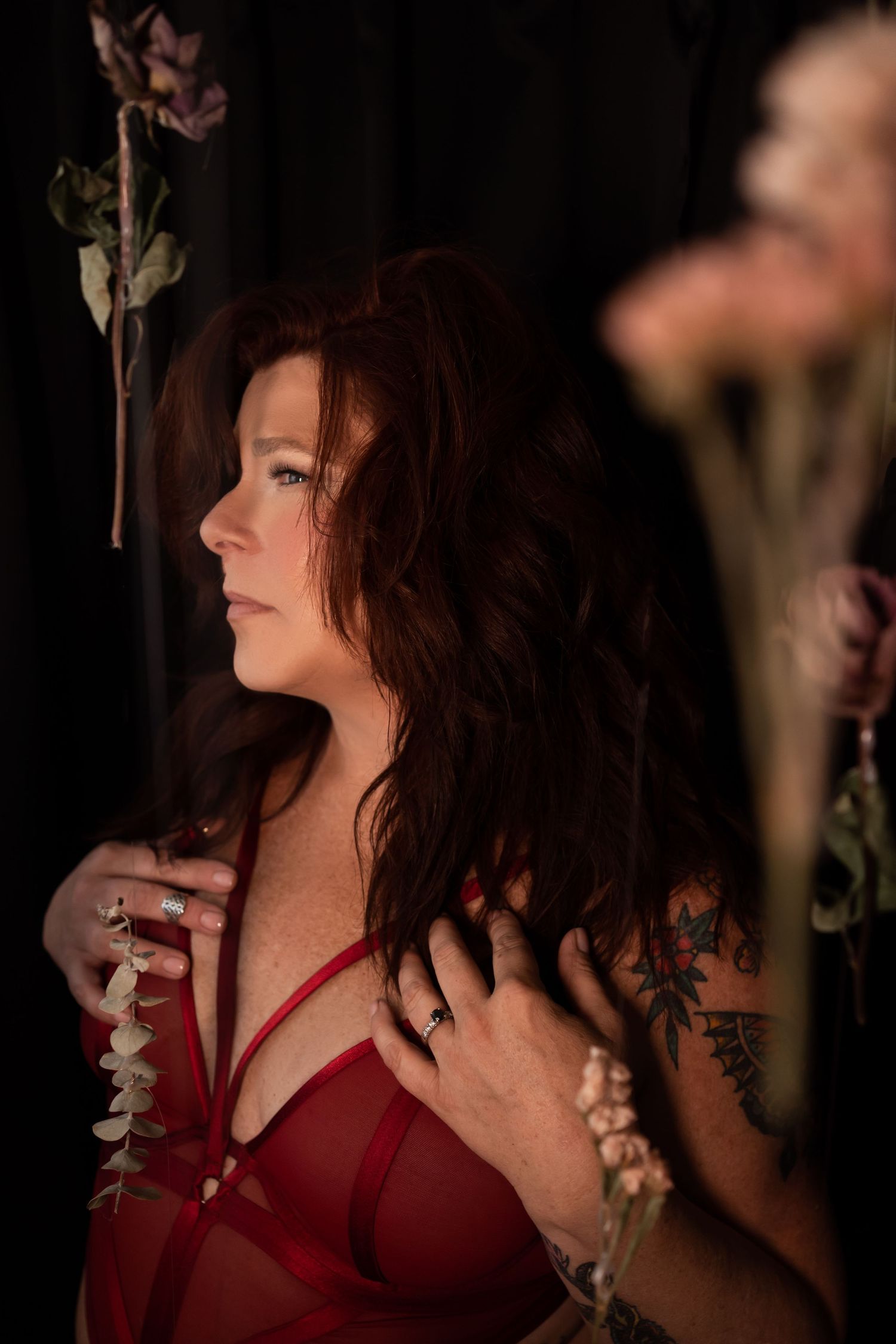 Romantic boudoir portrait with red lingerie and floral elements.
