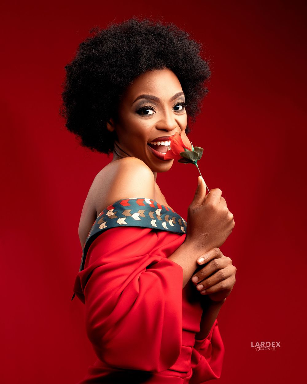 Joyful portrait with natural afro hairstyle holding chocolate against red background.