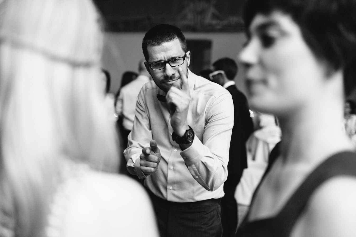 Black and white candid photo of guests interacting at an indoor celebration.