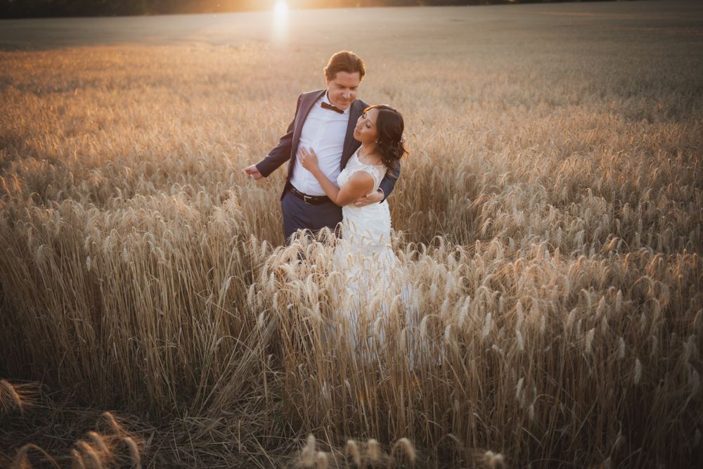Wedding couple sharing romantic moment in wheat field during golden hour.