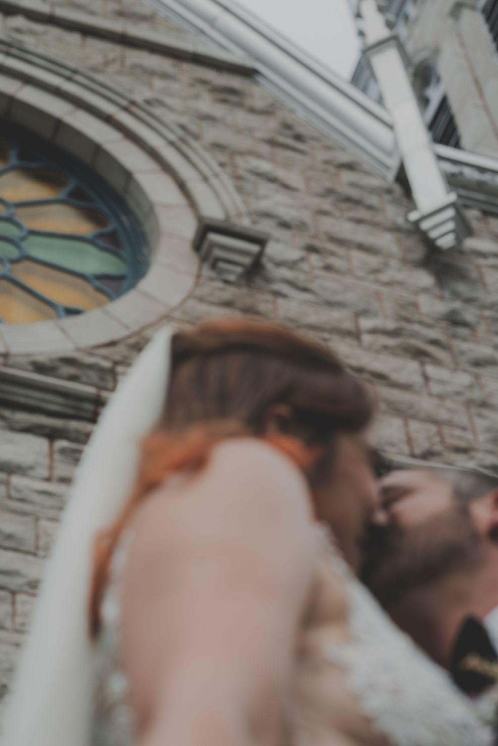 Close-up artistic wedding photo against stone church architecture.