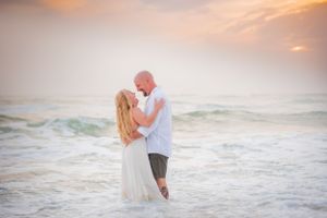 couple embracing in the water during fun engagement photoshoot in Panama City Beach Florida at sunset