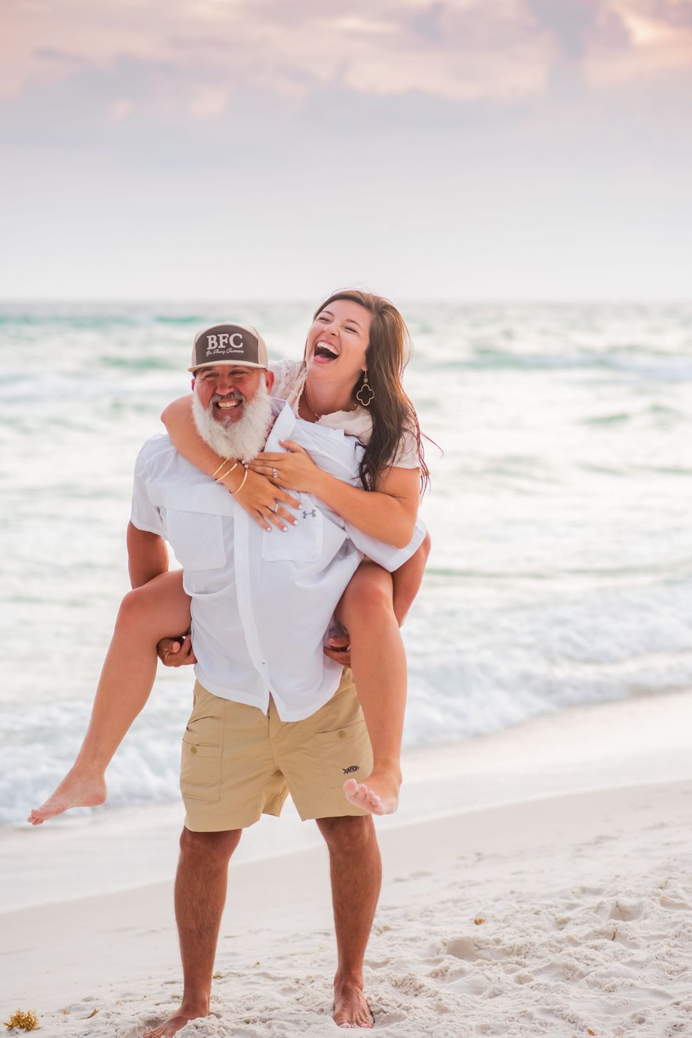 couple laughing on the beach her during fun candid engagement photoshoot in Panama City Beach Florida at sunset