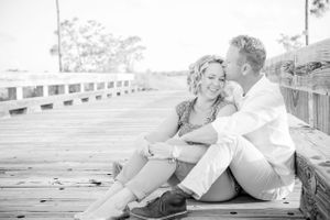 couple sitting on dock kissing during engagement photoshoot in Panama City Florida