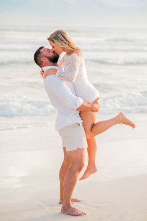 couple kissing on the beach as he holds her during engagement photoshoot in Panama City Beach Florida at sunset