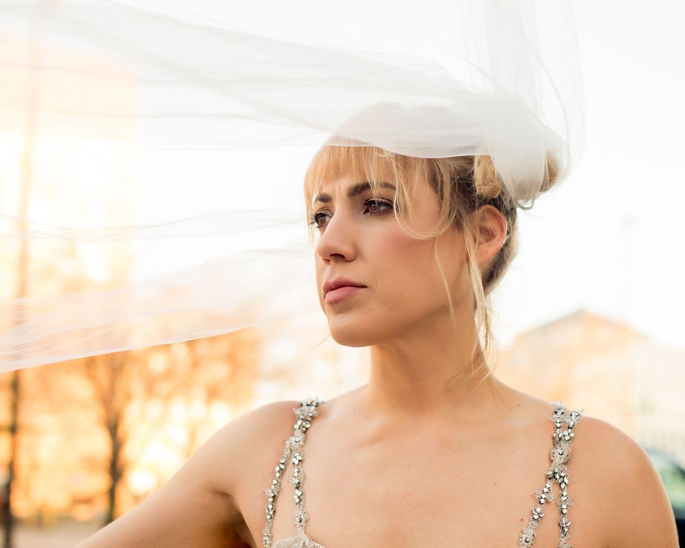Close-up portrait of someone wearing a sparkly wedding dress and veil at sunset.