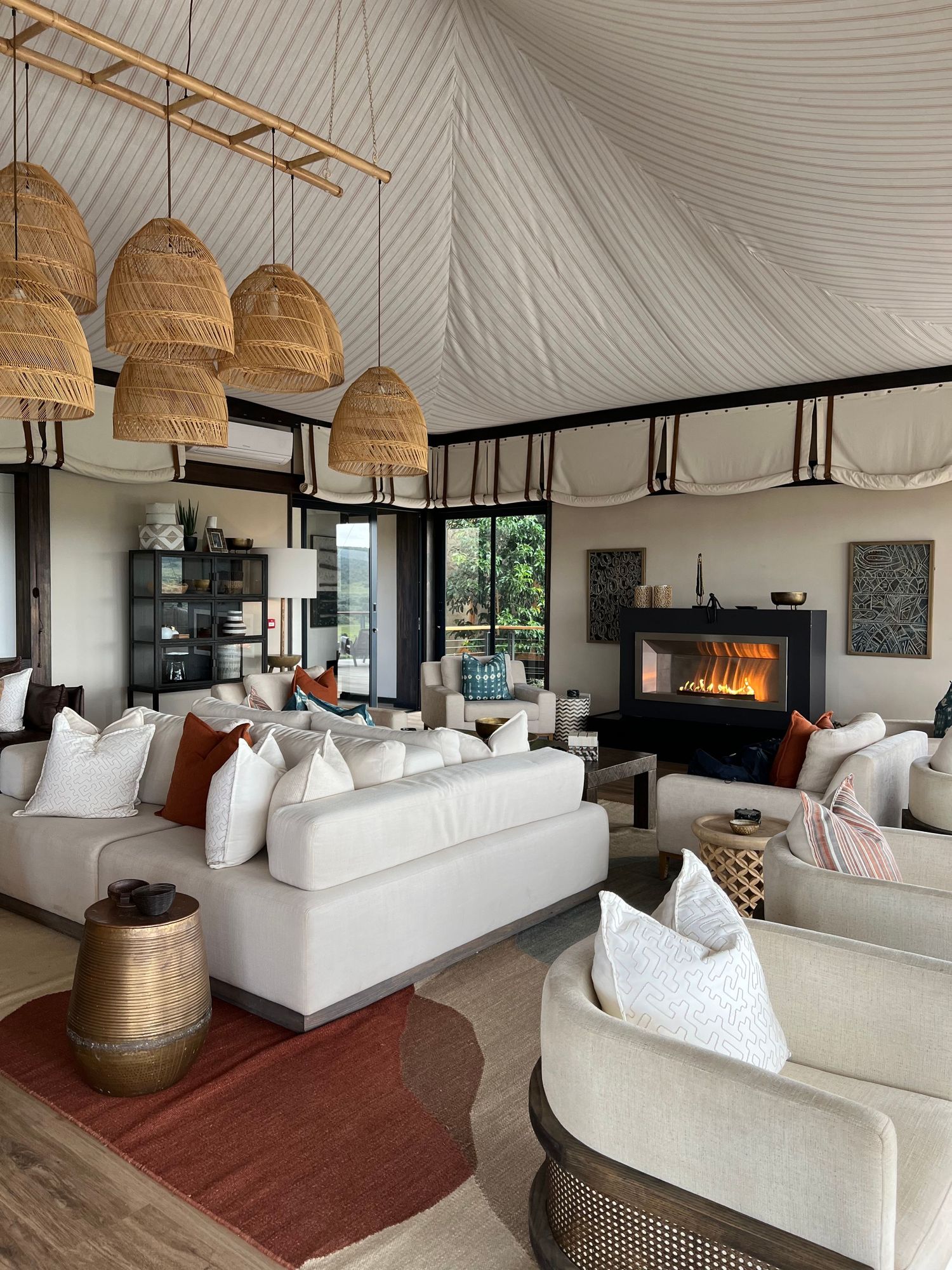 Elegant lounge area with white sofas, woven pendant lights and modern fireplace under vaulted ceiling.