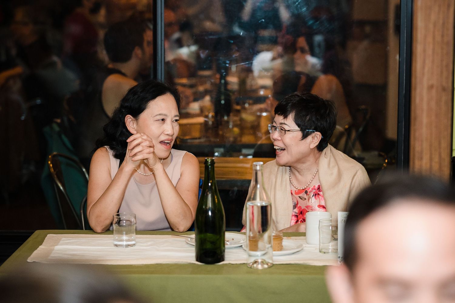 Two guests share a candlelit conversation at a rustic restaurant table.