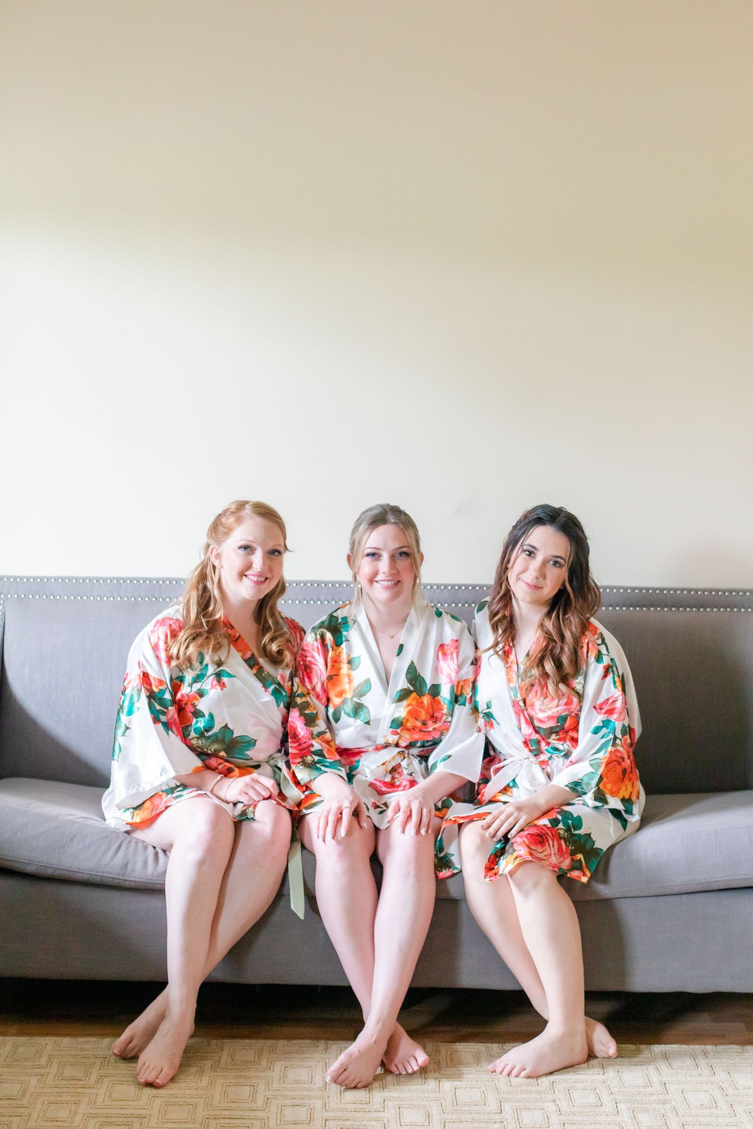 Three people in matching floral robes sitting casually on a gray couch.