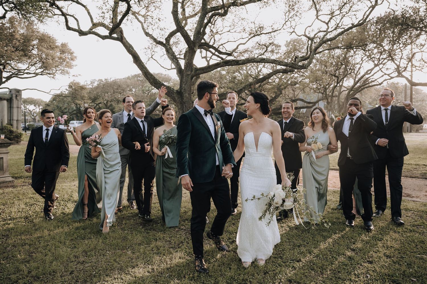 Wedding party walks together on lawn with historic building in background.