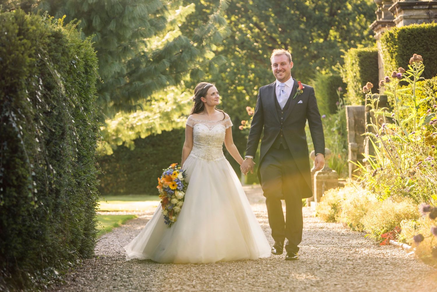 magical moments and bride and groom walk together in the hoar cross hall gardens