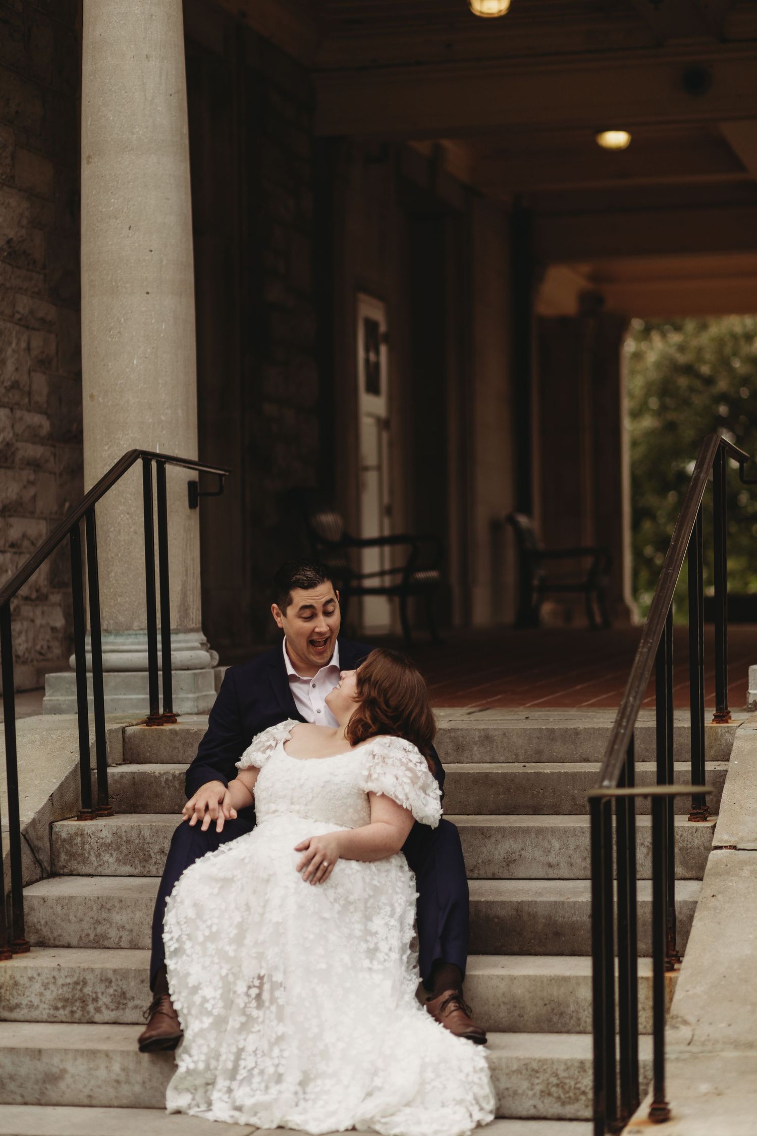 A couple shares a romantic moment while seated on concrete steps during their wedding.