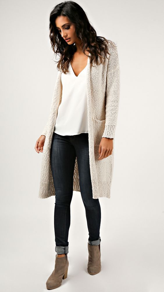 Stylish winter outfit with long beige cardigan, white blouse, dark skinny jeans and suede booties.
