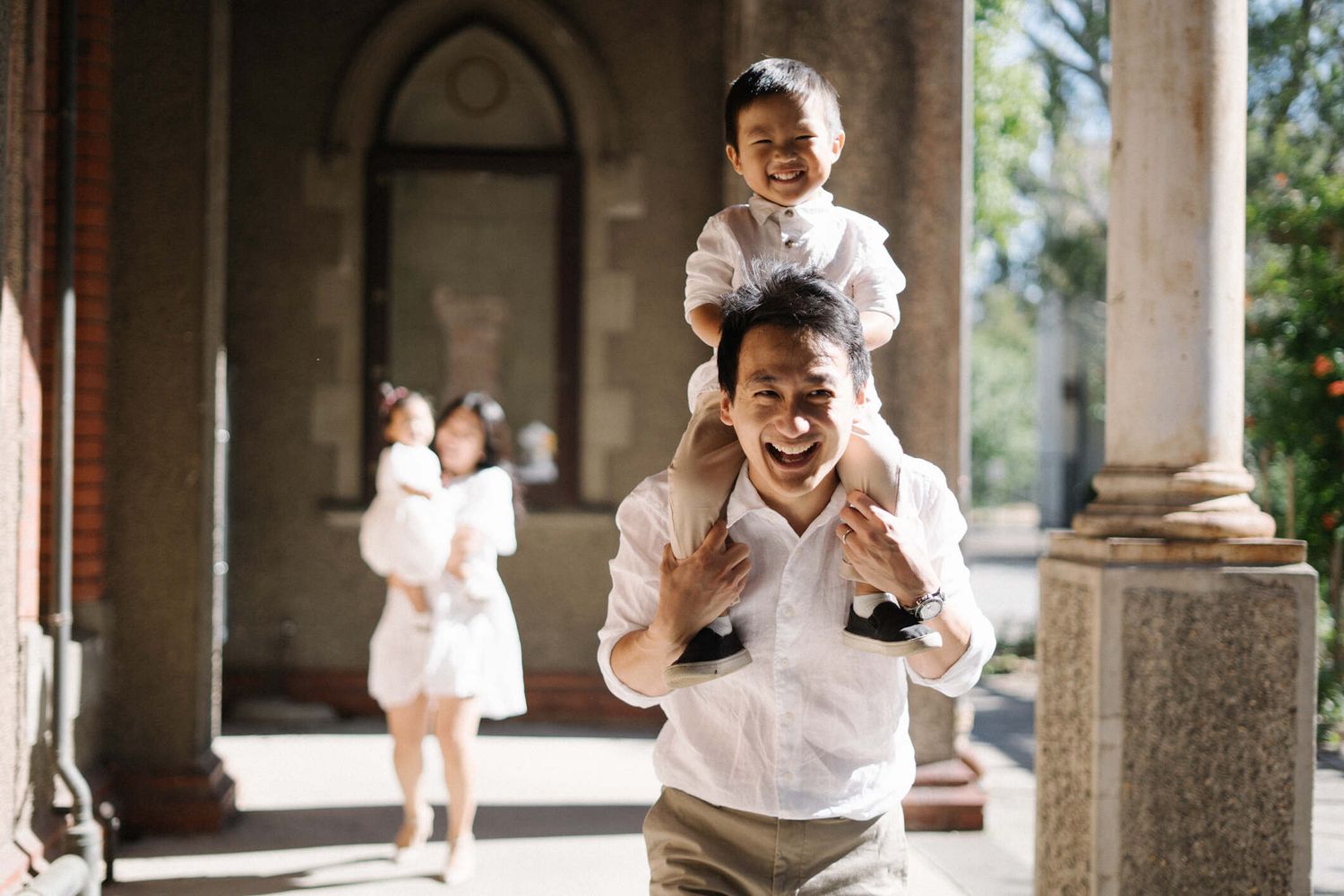 Dad smiling as he carries his daughter on his shoulders.