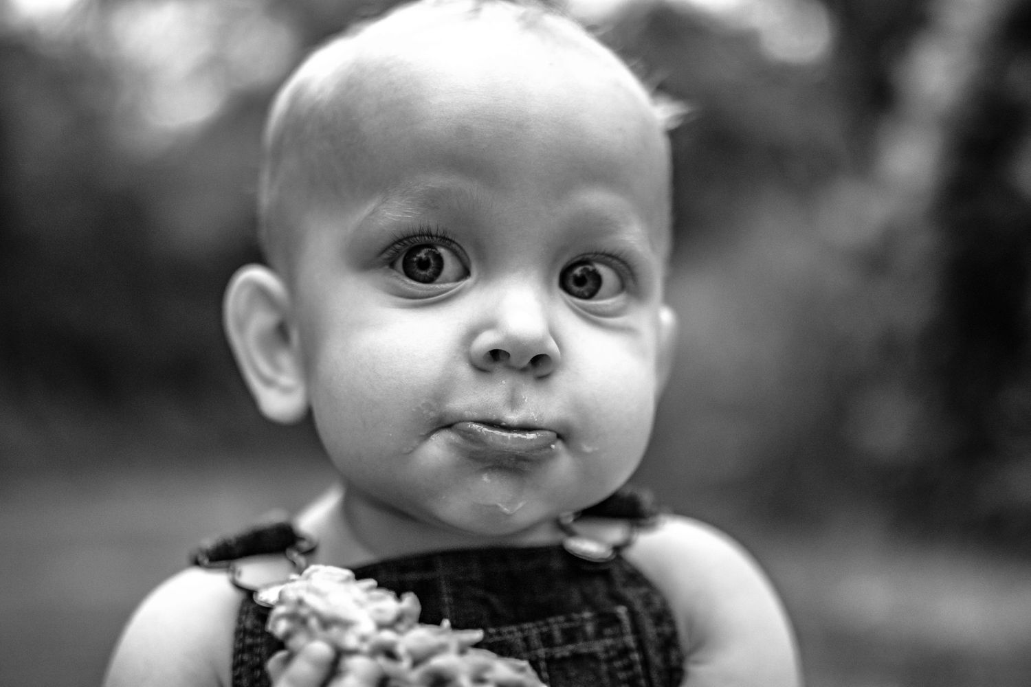 Black and white close-up portrait showcasing playful expression against blurred background.