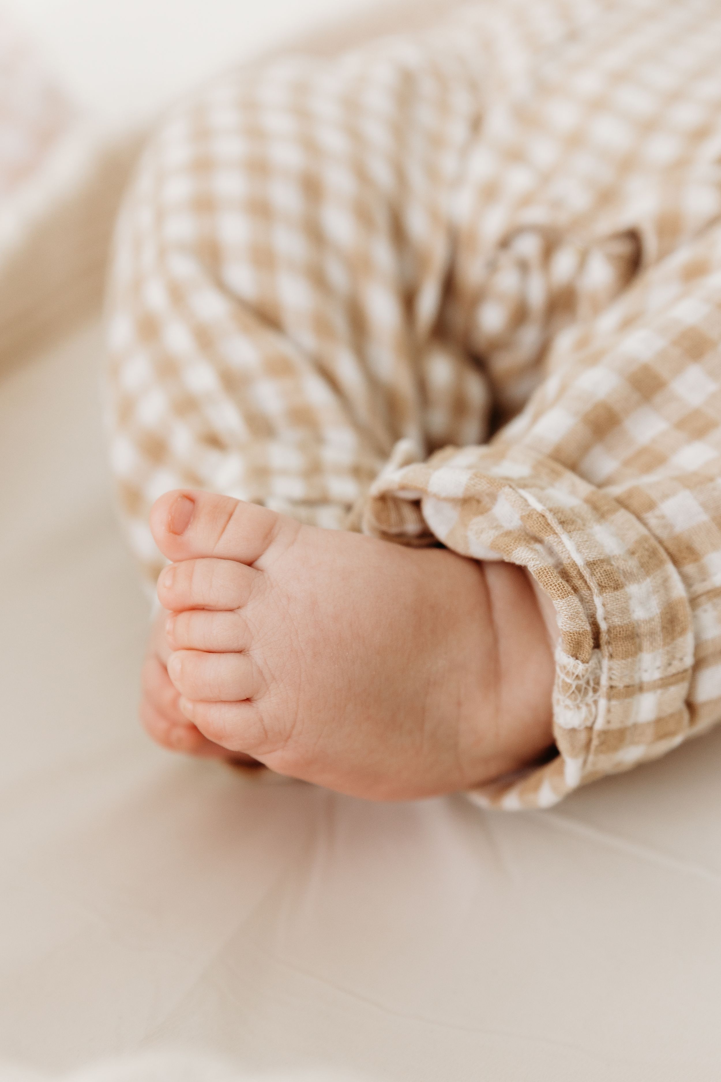 Close-up of baby feet wearing gingham fabric clothing.