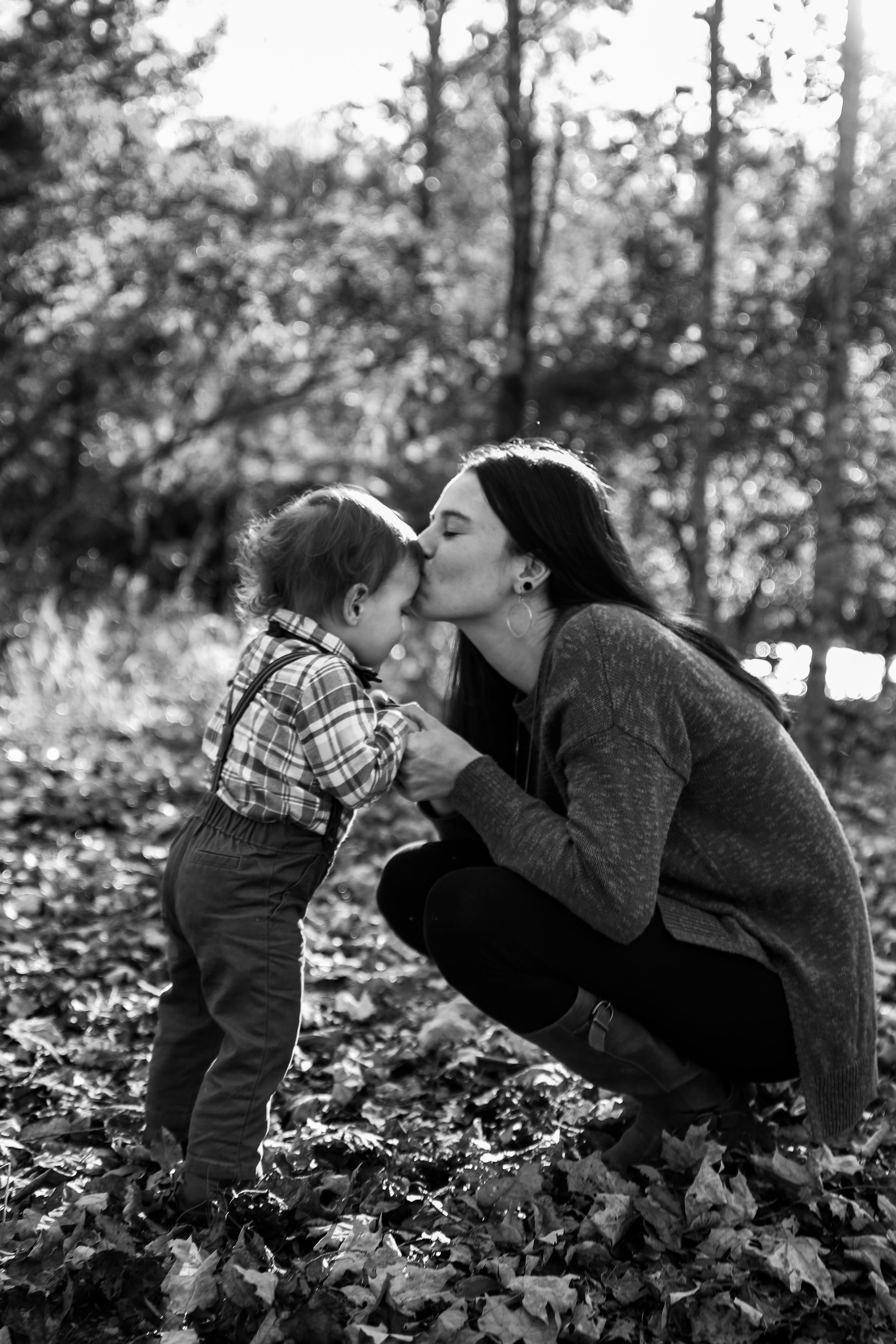 Sweet candid moment captured between parent and child among fallen autumn leaves.