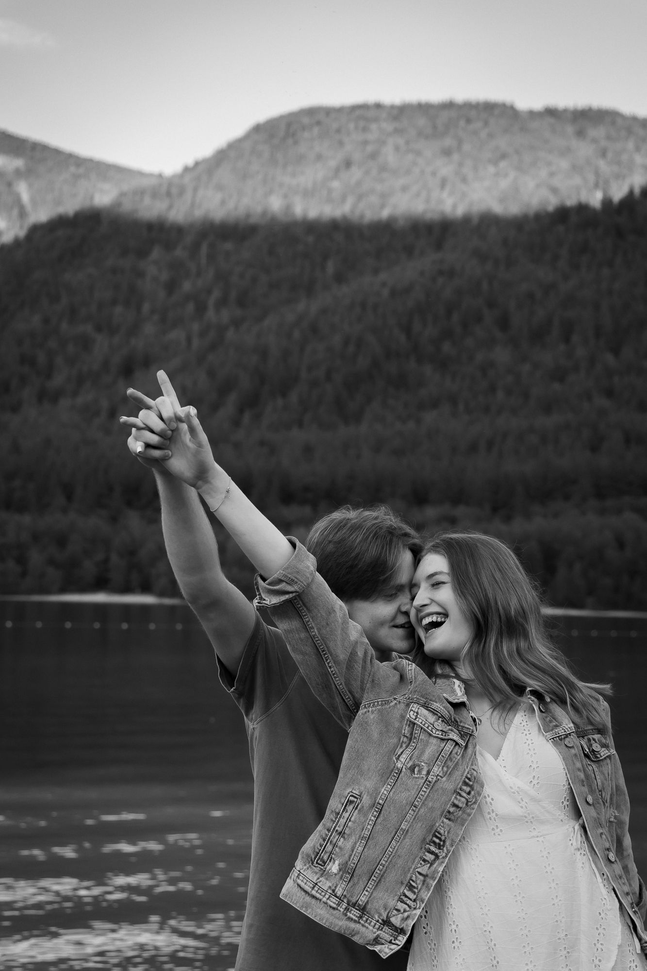 A man and woman dance together, mountains behind them, hands in the air - holding each other, smiling wide.