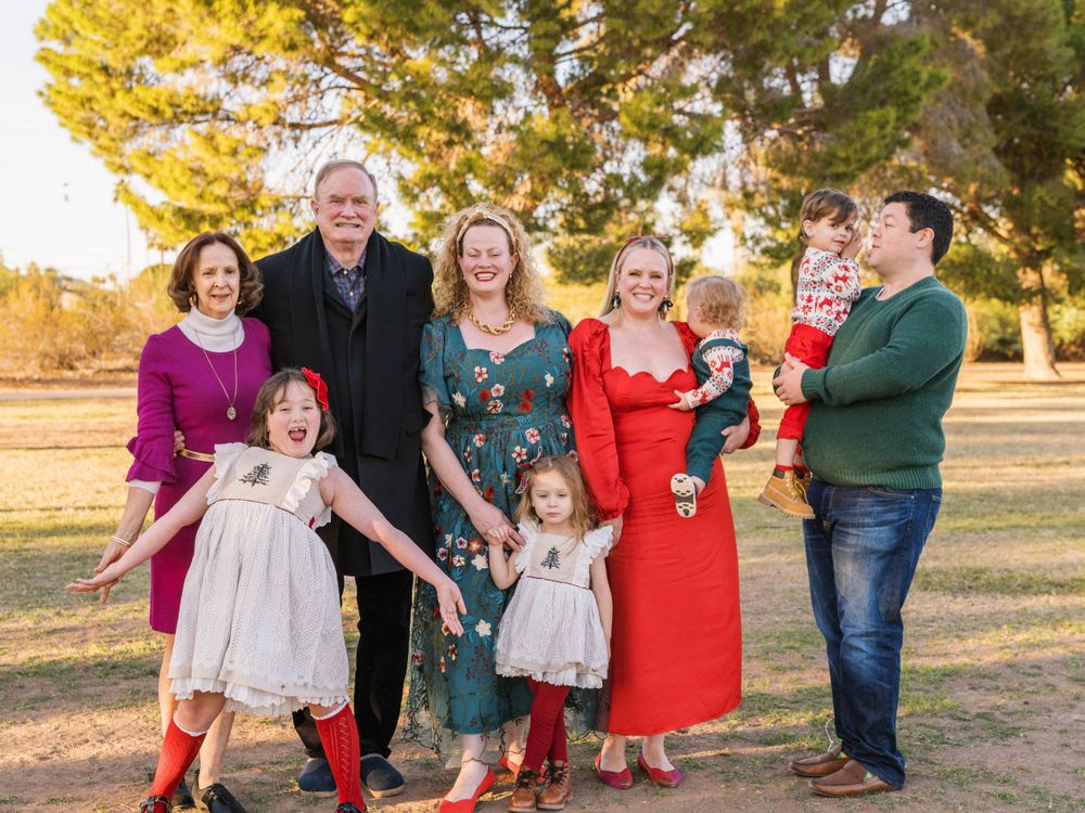 Extended family gathers for a joyful outdoor portrait during sunset.