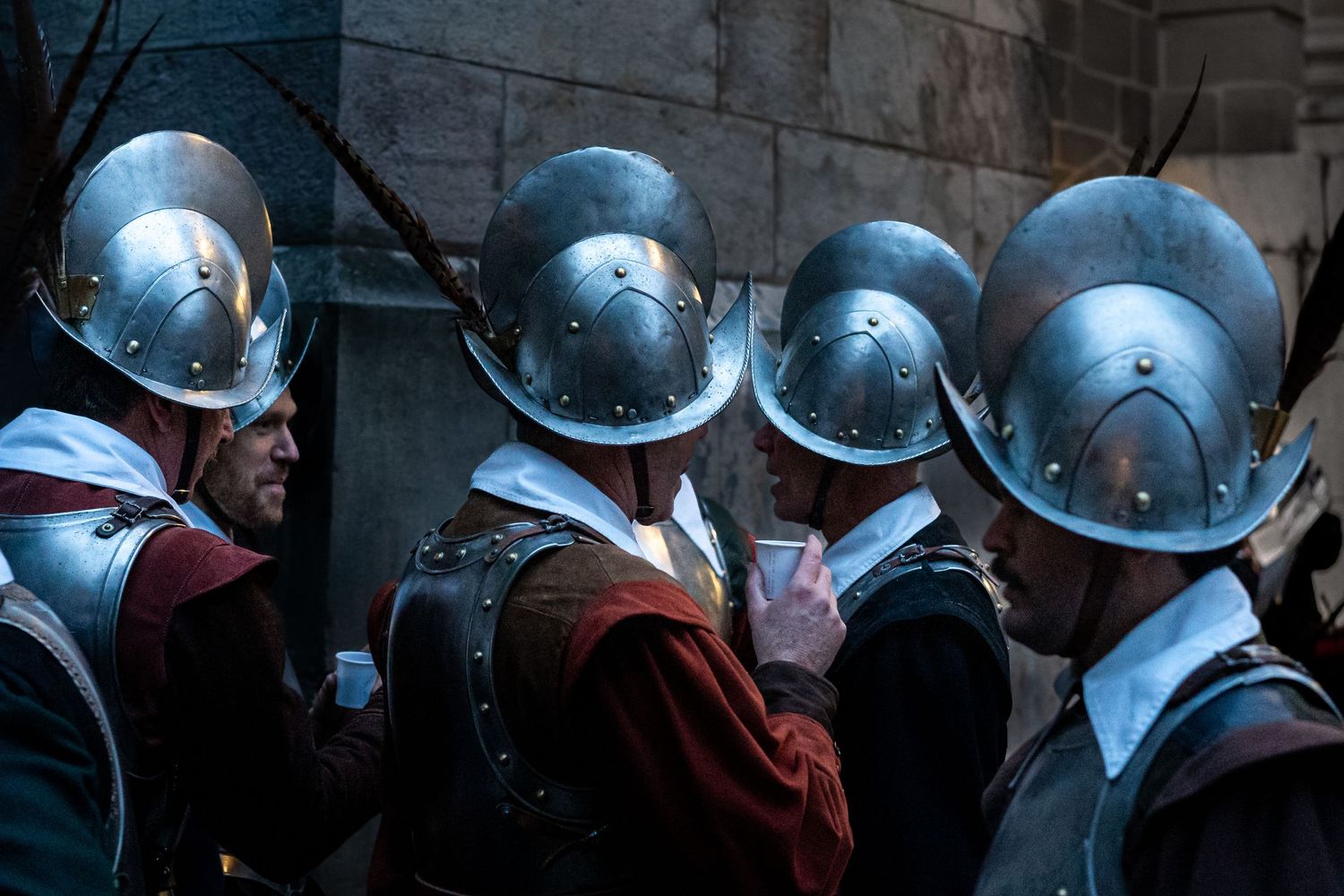 Medieval guards wearing silver helmets and red robes stand in formation during a historical reenactment.