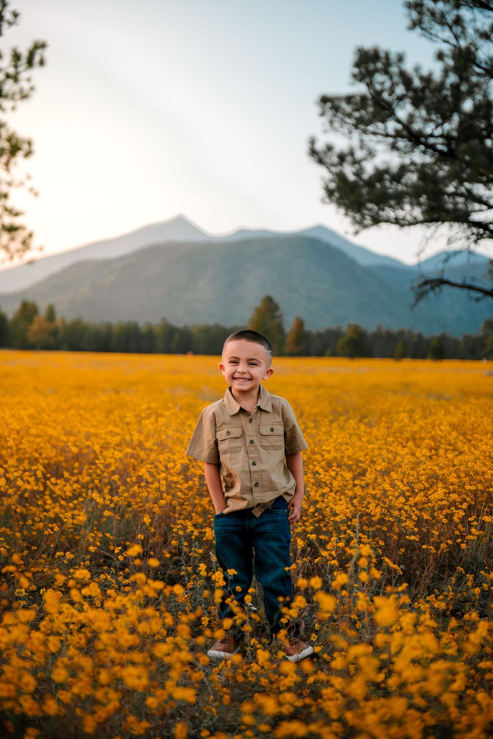 Child playing in stunning field of yellow wildflowers with mountain backdrop.